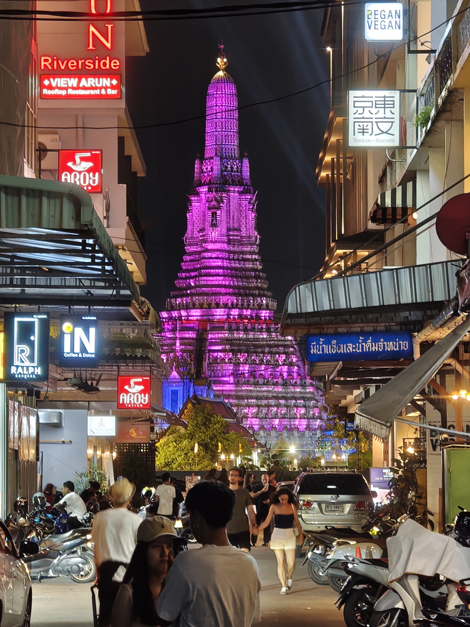 A narrow alley in Bangkok's old town opening onto a view of Wat Arun across the river